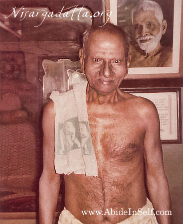 013-0-Nisargadatta Maharaj with a photo of Sri Ramana Maharshi behind.jpg